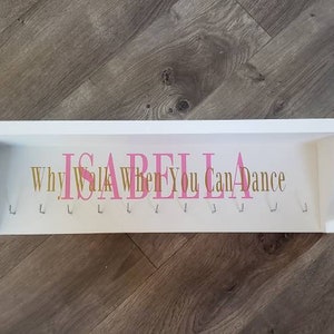May include: White wooden shelf with hooks and the text "Why Walk When You Can Dance" and the name "Isabella" in pink letters.