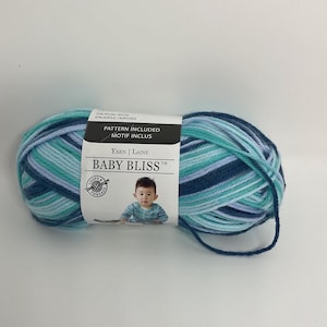 May include: A skein of blue, green, and white yarn with a label that reads "Baby Bliss" and includes a pattern. The label also says "Yarn | Laine" and "Pattern Included | Motif Inclus".