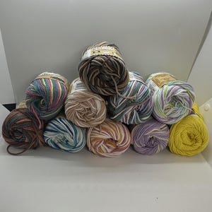May include: A collection of yarn skeins in various colors, including brown, blue, yellow, and purple. The yarn is arranged in a pile, showcasing the different color combinations and textures. Ideal for knitting and crochet projects.
