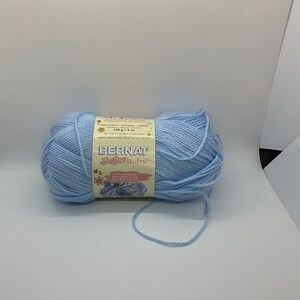 May include: A ball of light blue Bernat Softee Baby yarn. The label indicates the yarn is 140 g / 5 oz. The yarn is a soft, baby-friendly acrylic. The yarn is ideal for knitting or crocheting baby blankets, clothing, and accessories.