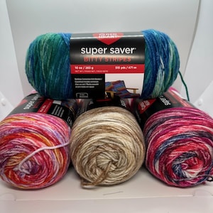 May include: A collection of Red Heart Super Saver yarn skeins in various colors. The top skein is labeled "Bitty Stripes" and weighs 10 oz (283 g). Other skeins feature shades of pink, brown, and blue. The yarn is suitable for knitting and crochet projects.