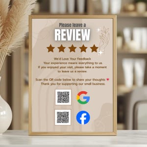 May include: A framed sign with the text "Please leave a REVIEW" and five brown stars. The sign includes a message encouraging reviews and QR codes for Google and Facebook. The sign is in a light brown frame.