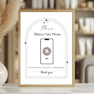 May include: A framed sign with a wooden frame. The sign reads "Please Silence Your Phone" above a graphic of a phone with a muted speaker icon. Below the phone graphic, it says "To Maintain a Peaceful Atmosphere. Thank you."