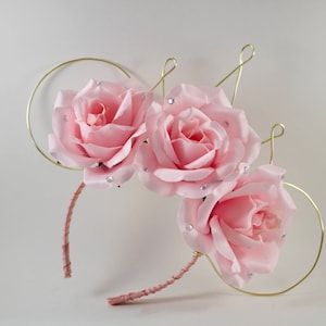 May include: Pink fabric roses with gold wire and rhinestones on a headband.