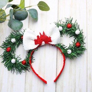 May include: A red headband with a white bow and a red castle silhouette. The headband is decorated with green garland and red and white ornaments.