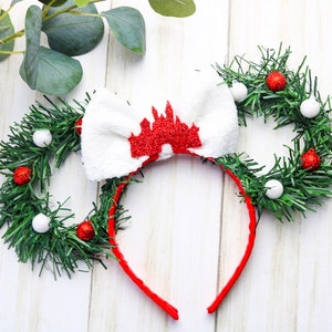 May include: A red headband with a white bow and a red glitter castle design. The headband is decorated with two green wreaths with red and white ornaments.