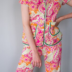 May include: A pink, orange, and green patterned pajama set with a button-up top and wide-leg pants.