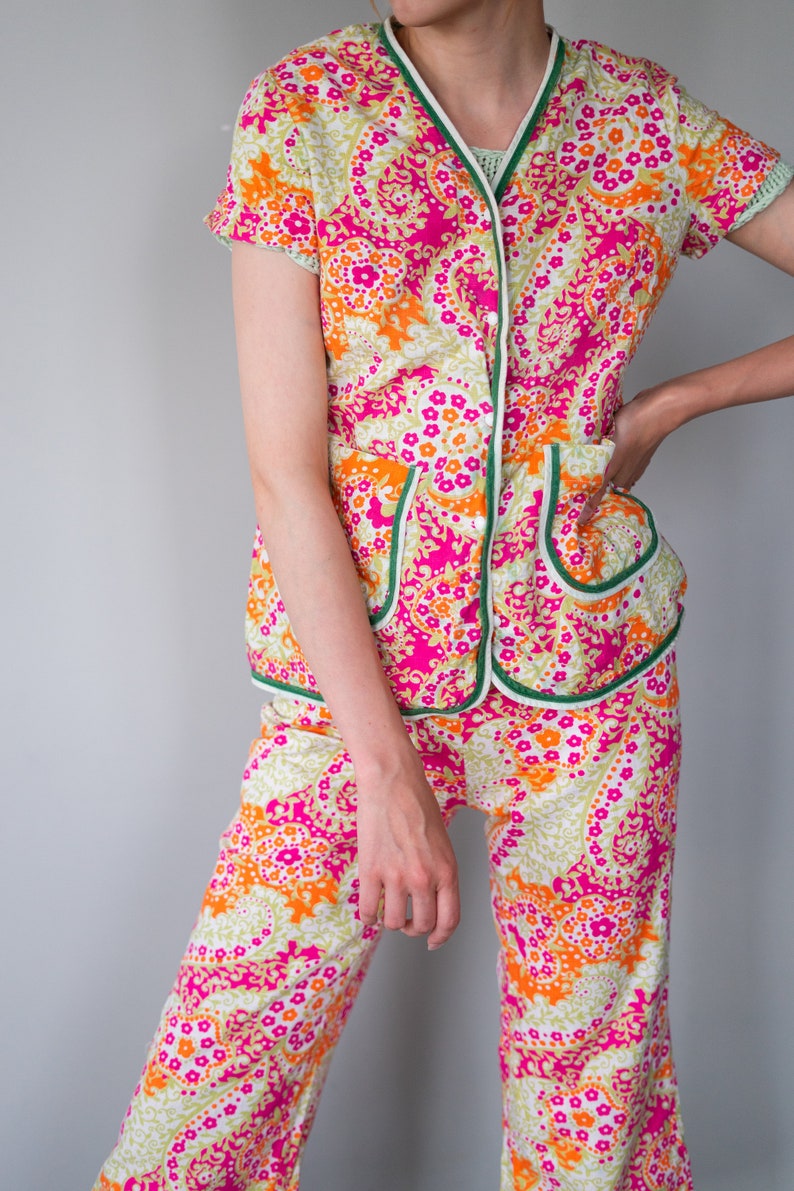 May include: A pink, orange, and green patterned pajama set with a button-up top and wide-leg pants.