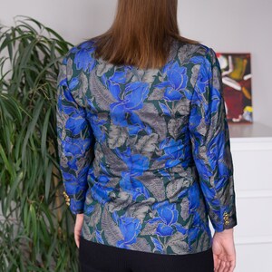 May include: A blue and green floral print blazer with gold buttons. The blazer has a fitted silhouette and long sleeves.