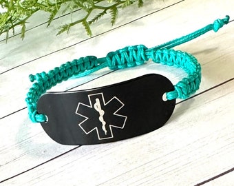 May include: A teal braided bracelet with a black medical ID tag featuring a white star of life symbol.