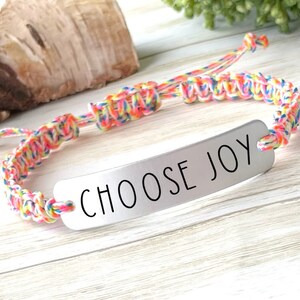 May include: A colorful braided bracelet with a silver charm that says "CHOOSE JOY".