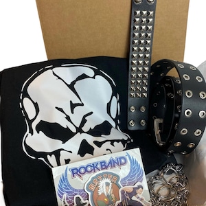 May include: A brown cardboard box filled with a black t-shirt with a white skull graphic, a black studded bracelet, a black belt with silver eyelets, a silver chain, and a Rock Band Master sticker with a blue and purple background.