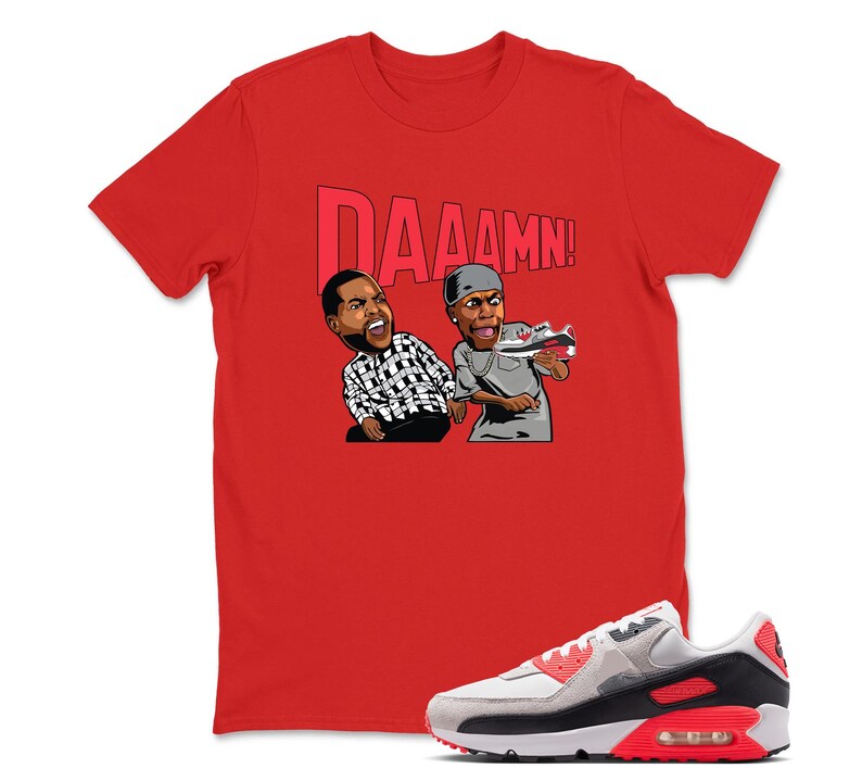 May include: Red t-shirt with the word "DAAAMN!" above a cartoon graphic of two men. One man is wearing a black and white checkered shirt, and the other is holding a sneaker. A gray, white, and red sneaker is in the foreground.