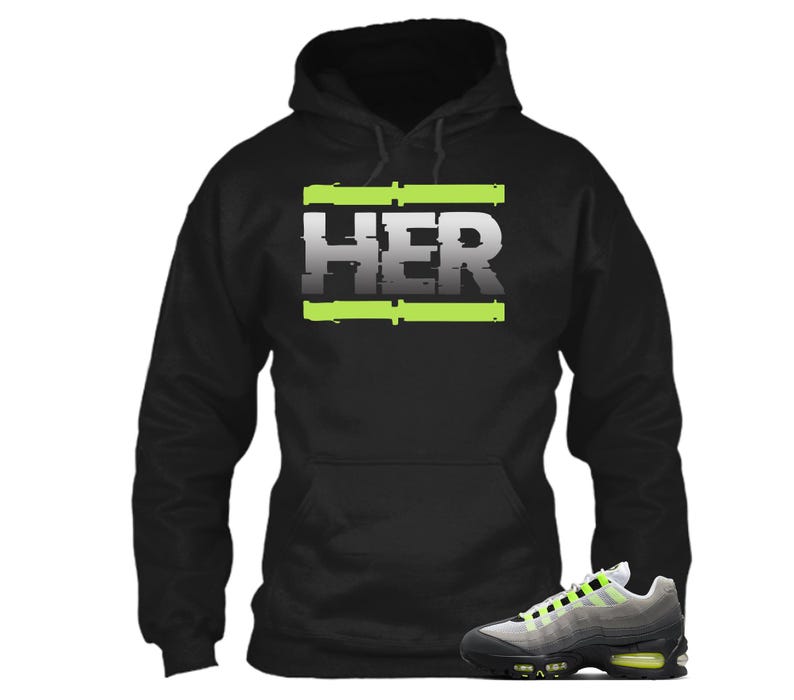 Pu&ograve; includere: Felpa con cappuccio nera con la scritta "HER" in bianco, bordata di verde neon. Un paio di scarpe da ginnastica grigie, nere e verde neon sono in primo piano. La felpa ha un cappuccio con coulisse e una tasca frontale.