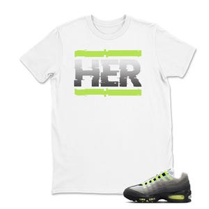 Pu&ograve; includere: T-shirt bianca con la scritta "HER" in un font grigio in stile glitch, accentuata da barre orizzontali verde neon. Un paio di scarpe da ginnastica grigie e nere con dettagli verde neon in primo piano.