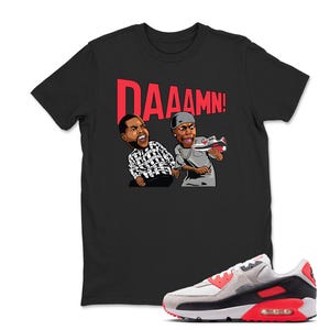 May include: Black t-shirt with a graphic of two cartoon figures and the word "DAAAMN!" in red. A pair of Air Max 90 sneakers in white, gray, black, and red are in the foreground.