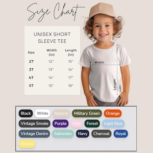 May include: A child wearing a white unisex short sleeve tee, with a size chart showing measurements in inches. The chart lists sizes 2T to 5T, with width and length measurements. Color options include black, white, and various other colors.
