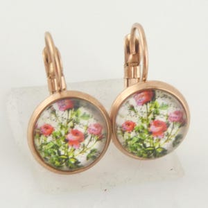 May include: A pair of rose gold earrings with a floral design. The earrings are round and have a small hook closure.