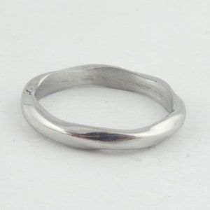 Könnte beinhalten: Ein silberner Ring mit einem wellenförmigen, organischen Design. Der Ring ist glatt und poliert.