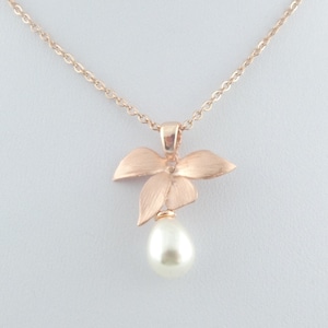 Può includere: Una collana in oro rosa con un delicato ciondolo a forma di fiore e una goccia di perla.