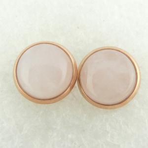 Könnte beinhalten: Ein Paar Ohrstecker aus Roségold mit runden, hellrosa Steinen.