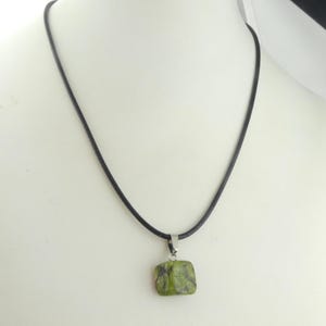 May include: A green and black stone pendant on a black cord necklace.