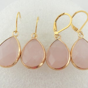 Könnte beinhalten: Ein Set mit drei goldfarbenen Ohrringen mit rosafarbenen tropfenförmigen Steinen. Die Ohrringe haben ein schlichtes Design und sind perfekt für den Alltag.