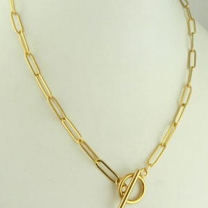 May include: A gold chain necklace with a toggle clasp. The chain is made of oval-shaped links.