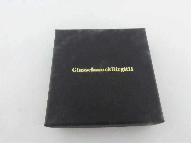 May include: Black box with the text "GlassmuckBirgitH" in gold lettering.