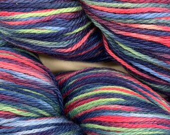 Könnte beinhalten: Nahaufnahme eines Knäuels bunter Wolle. Die Wolle weist eine Mischung aus Farben auf, darunter tiefes Blau, Lila, Rot, Grün und Hellblau. Die Wolle ist eng gewickelt und zeigt die Textur und Farbvariationen. Ideal für Strick- und Häkelprojekte.