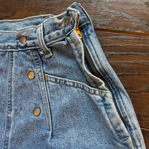 May include: A pair of light blue denim jeans with a zipper fly and button closure. The jeans have a high waist and a straight leg.