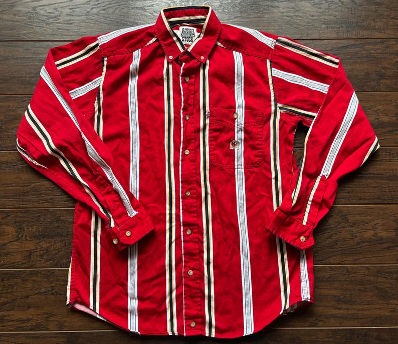 May include: A red, white and black striped long-sleeved button-down shirt with the text "Famous Players Stick" on the front.