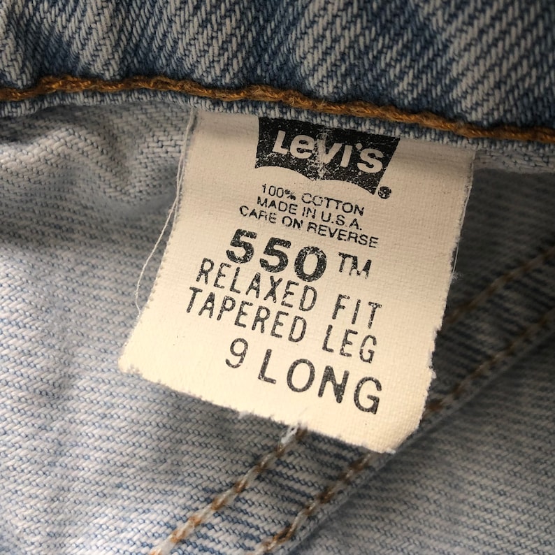May include: A white Levi's jeans label with the text "550 TM Relaxed Fit Tapered Leg 9 Long" and "100% Cotton Made in U.S.A. Care on Reverse".