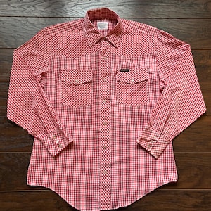 May include: A red and white gingham long-sleeved shirt with two front pockets and buttoned cuffs. The shirt features a classic collar and a Western design. The fabric appears to be cotton or a similar material.