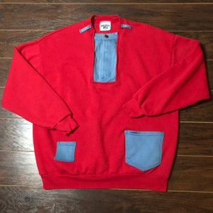 May include: Red sweatshirt with a denim panel on the front and two denim pockets on the bottom. The sweatshirt has a high neck and a ribbed collar.
