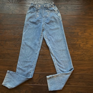 May include: Light blue high-waisted jeans with a button fly and silver buttons. The jeans have a straight leg and are made of a soft denim fabric.