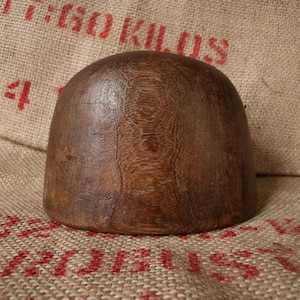 May include: A dark brown wooden hat block, a tool used for shaping hats.
