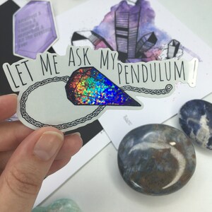 May include: A sticker with a holographic crystal pendulum and the text "Let me ask my pendulum!" on a white background.