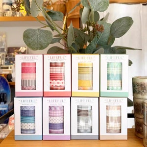 Può includere: Otto rotoli di washi tape in scatole colorate. Ogni scatola ha un diverso motivo di washi tape. Le scatole sono etichettate "LIFEFUL" e "WASHI TAPE".