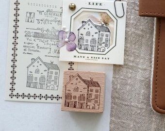 May include: A set of three wooden stamps featuring illustrations of houses. The stamps are rectangular and have a brown wood finish. The stamps are labeled "LIFE" and "HAVE A NICE DAY".