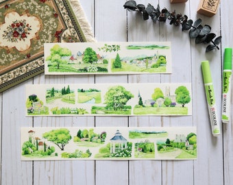 May include: Three sheets of decorative washi tape with watercolor illustrations of green landscapes, trees, and buildings. The tape is on a white wooden surface with two green markers.