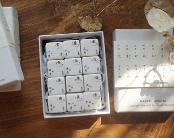 May include: White boxes with Japanese characters and text. One box is open, revealing small, rectangular tiles with black calligraphy. The boxes are labeled "HANEN STUDIO" and "Copyright reserved by Hanen Studio."