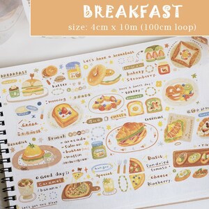 May include: A white washi tape with a repeating pattern of breakfast foods, including croissants, toast, sandwiches, and fruit. The tape is 4 cm wide and 10 meters long, and the text "BREAKFAST" is printed on the tape.