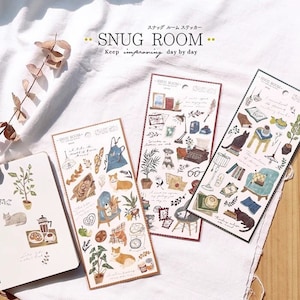 Könnte beinhalten: Drei Blätter mit Aufklebern, die Illustrationen von gemütlichen Zimmern zeigen, darunter ein Hund, eine Katze, Bücher, Pflanzen und Möbel. Die Aufkleber sind mit "SNUG ROOM - Keep improving day by day" beschriftet.