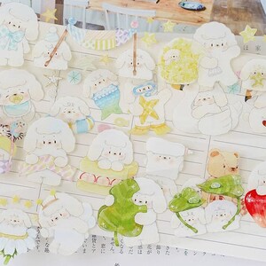 Op de afbeelding: Een vel met witte stickers met illustraties van schattige witte honden in verschillende poses en outfits. De stickers zijn versierd met sterren, bloemen en andere schattige details.
