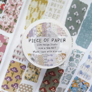 May include: A roll of washi tape with the text "PIECE OF PAPER" and "LCN Design Studio". The tape is 4 cm x 10 m and has a kiss-cut design. The background features various patterned washi tape strips.