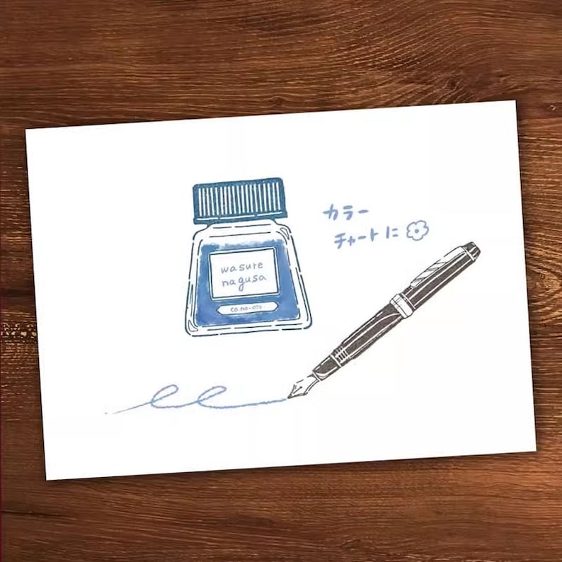 May include: A blue ink bottle with the text "wasure nagusa" and a black fountain pen with a blue ink line drawn on a white background. The text "カラーチャートに" is written in Japanese.