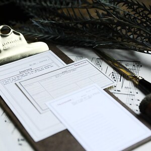 May include: A close-up of a clipboard with two blank white paper forms. The forms have lines and headings, including "Journey" and "No. 57". The clipboard is on a brown surface with a sheet of music and a silver letter opener.