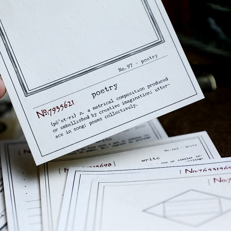 May include: A close-up of a white card with black text. The card has a black border and the text "No.97 - poetry" is printed in the top right corner. The text "N№:7935621" is printed in the top left corner. The word "poetry" is printed in large letters in the center of the card. The definition of the word "poetry" is printed below the word. The definition is "(p&otilde;'et-rı) n. a metrical composition produced or embellished by creative imagination: utterance in song: poems collectively."