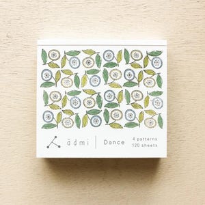 Peut inclure: Un bloc-notes blanc avec un motif floral dans des tons de bleu, vert et jaune. Le bloc-notes porte l'inscription "ä d mi | Dance 4 patterns 120 sheets" imprimée en bas.